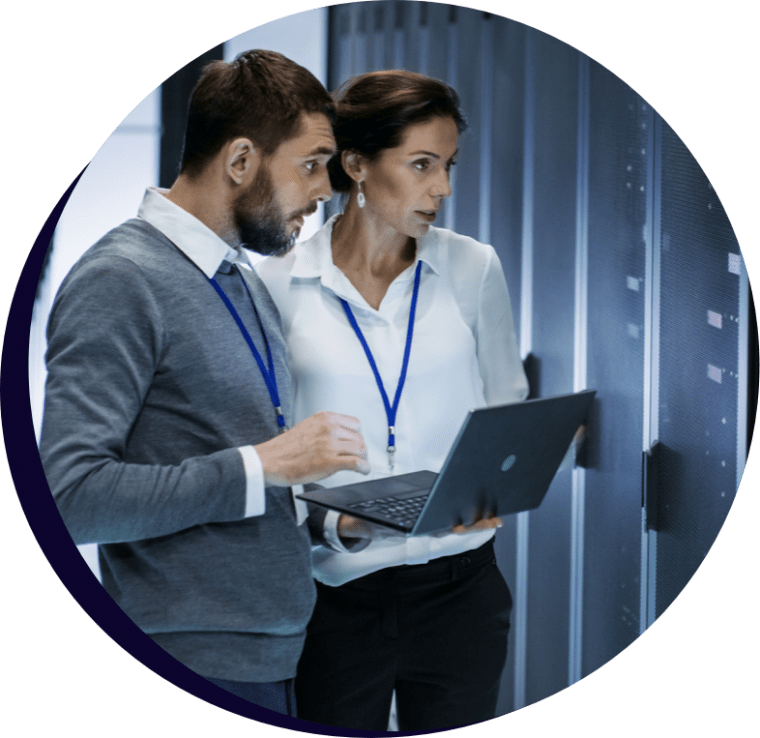 Man and woman looking at a large computer server and holding laptop