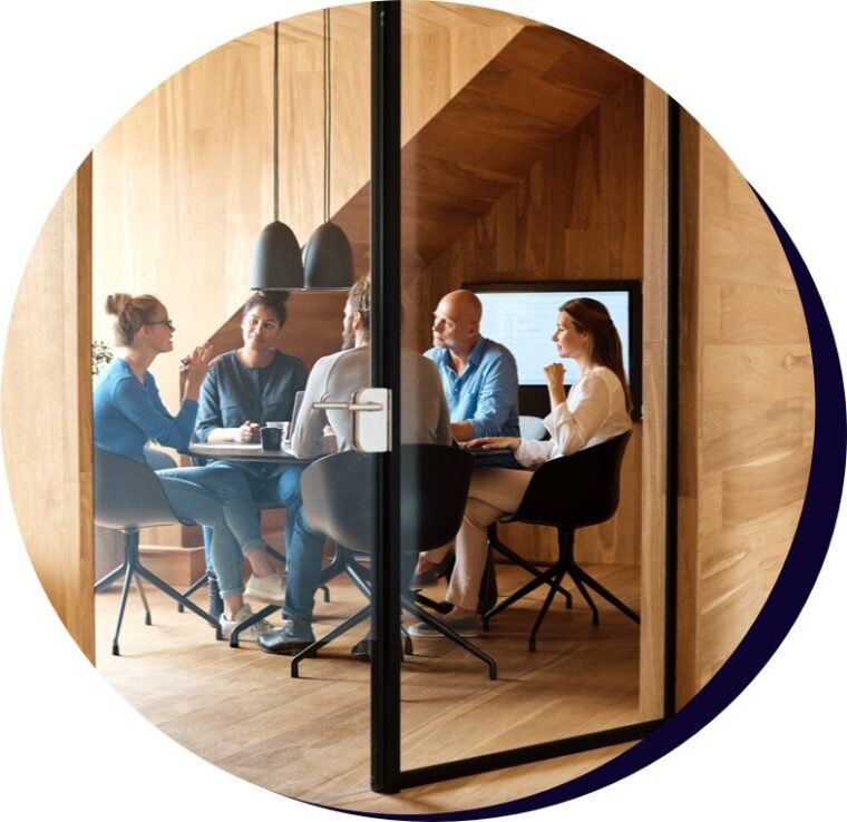 Two men and three women sitting around a round boardroom table.